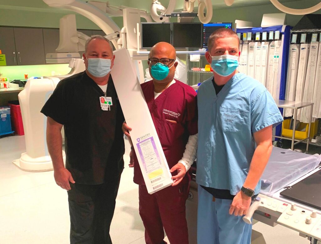 A group of CIS staff members in scrubs pose with a box containing the Sentry Bioconvertible Inferior Vena Cava (IVC) Filter