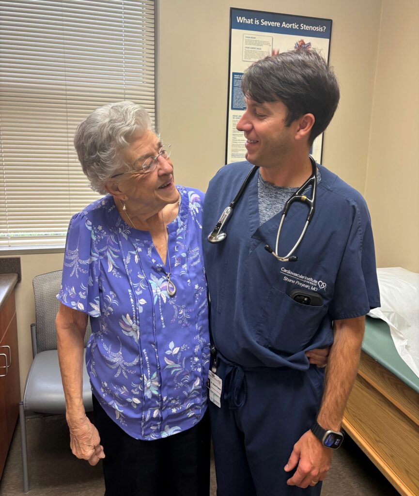 An elderly woman and a doctor share a light moment in a medical examination room.